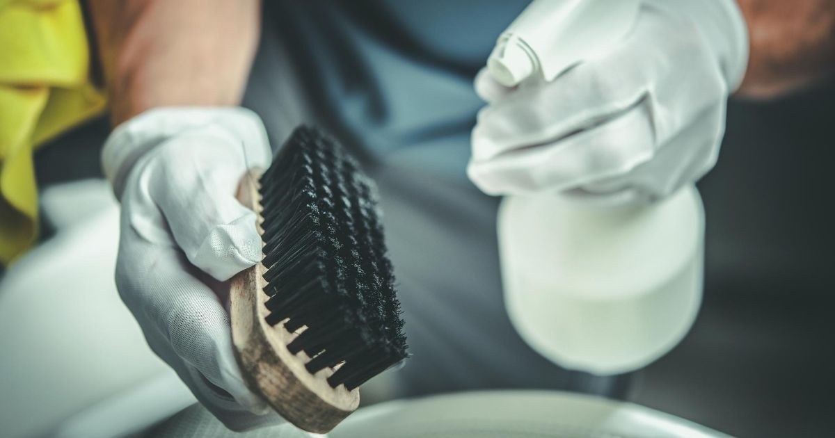 Κάποιος με γάντια ψεκάζει με υγρό μία βούρτσα καθαρισμού