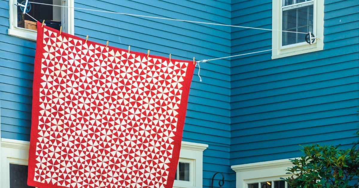 Ένα ασπροκόκκινο πάπλωμα απλωμένο σε σκοινί. Το σκοινί είναι δεμένο σε δύο παράθυρα.