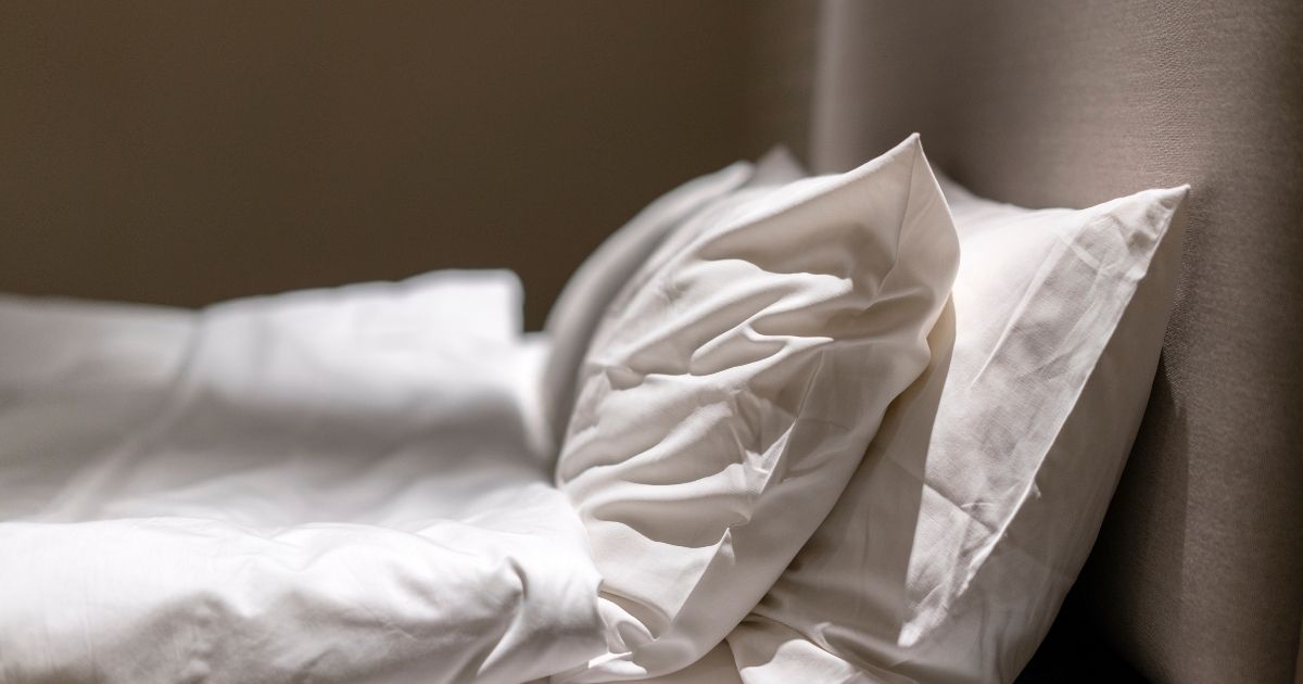 Κρεβάτι με λευκά μαξιλάρια και λευκό πάπλωμα.