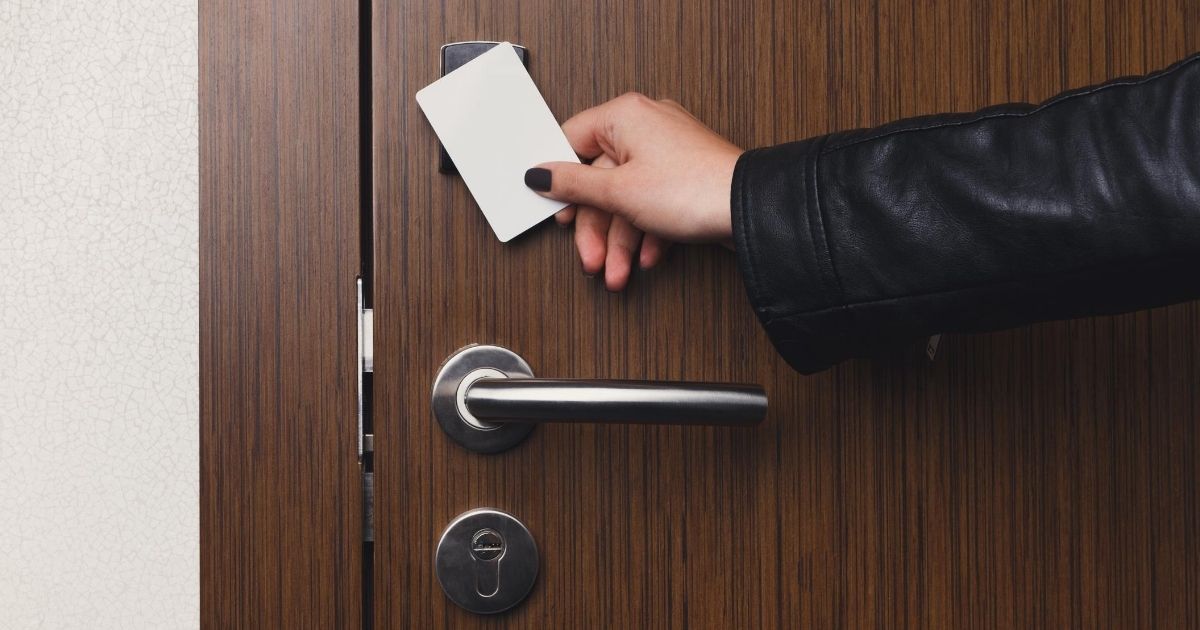 Ένα γυναικείο χέρι κρατώντας μια κάρτα, ανοίγει μια πόρτα ασφαλείας σπιτιού.