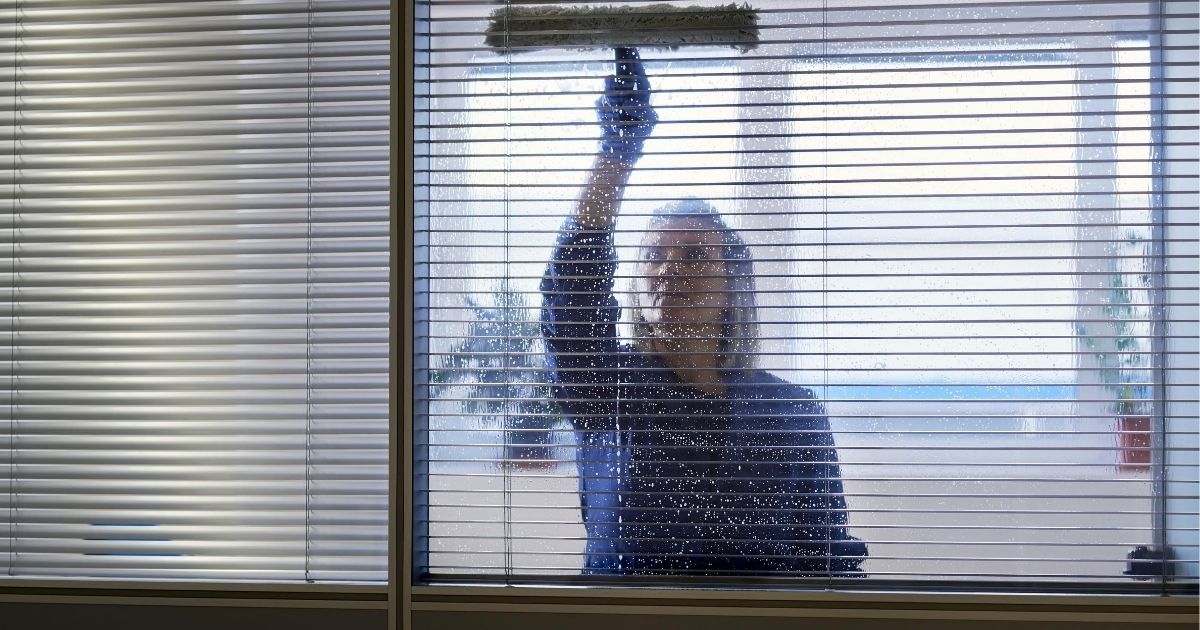 Μια επαγγελματίας γυναίκα, κθαρίζει τζάμι με ειδικό εργαλείο.