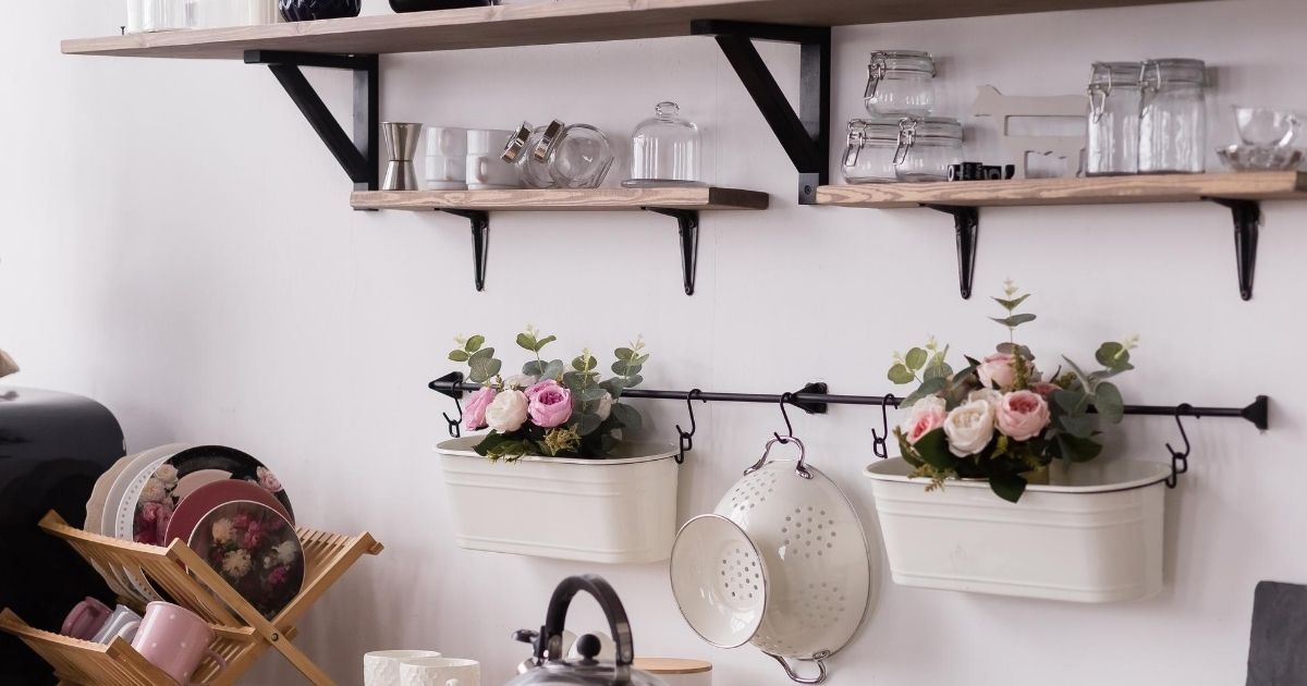 Τοίχος κουζίνας με ράφια διακοσμημένα και γλάστρες κρεμαστές σε σιδηρόδρομο τοίχου.