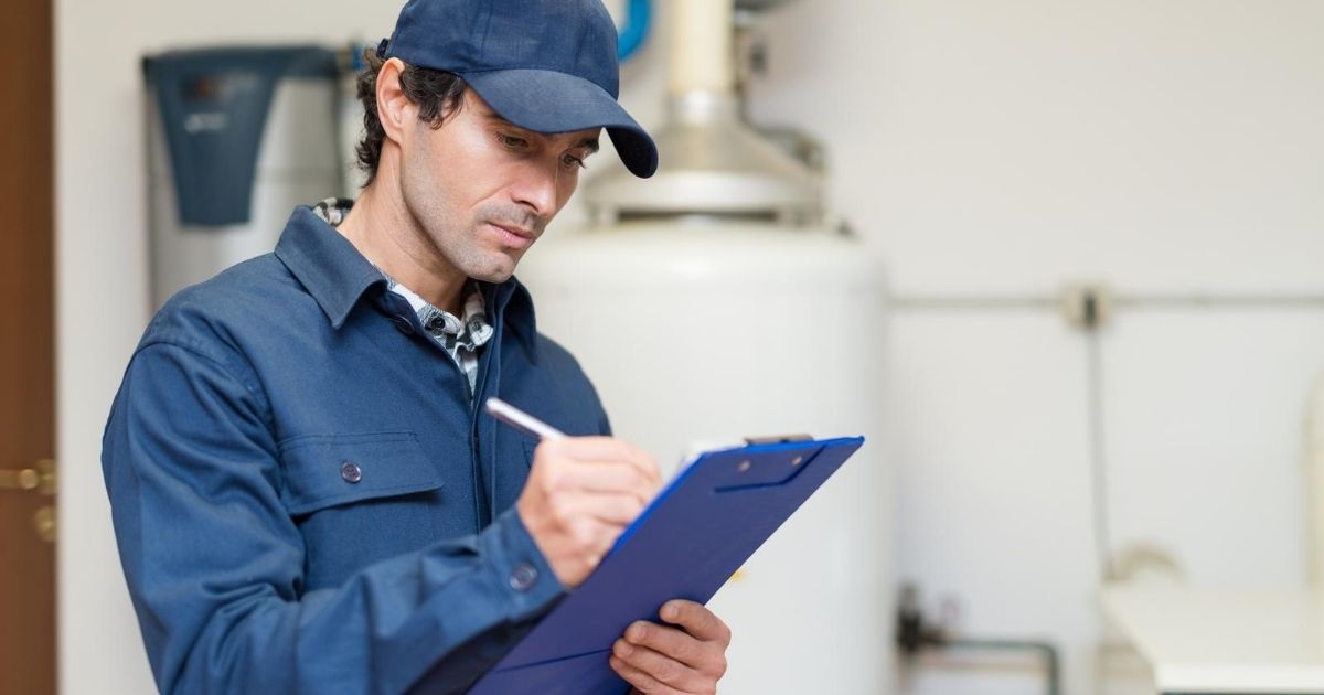 Ένας επαγγελματίας όρθιος μπροστά από θερμοσίφωνα σημειώνει σε ντοσιέ.