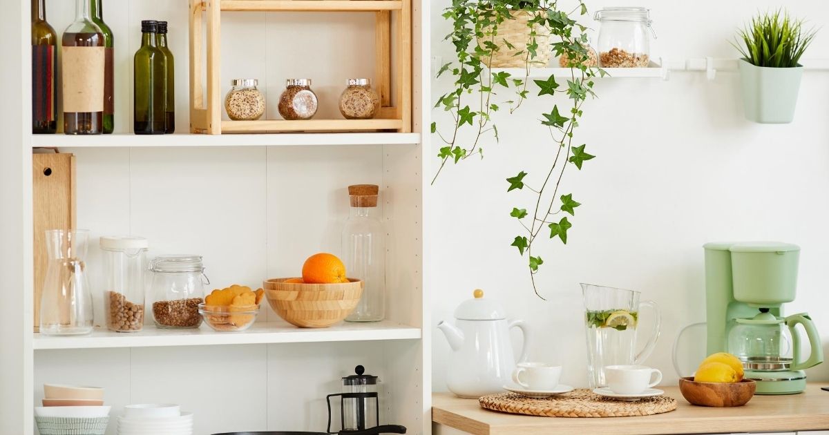 Μια ραφιέρα δίπλα σε τραπέζι κουζίνας με διάφορα πράγματα επάνω.