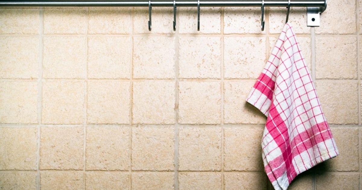 Ένας σιδερένιος σωλήνας με κρεμαστράκια για πετσέτες στον τοίχο. Μια καρώ πετσέτα κουζίνας κρέμεται σε ένα από τα κρεμαστράκια.